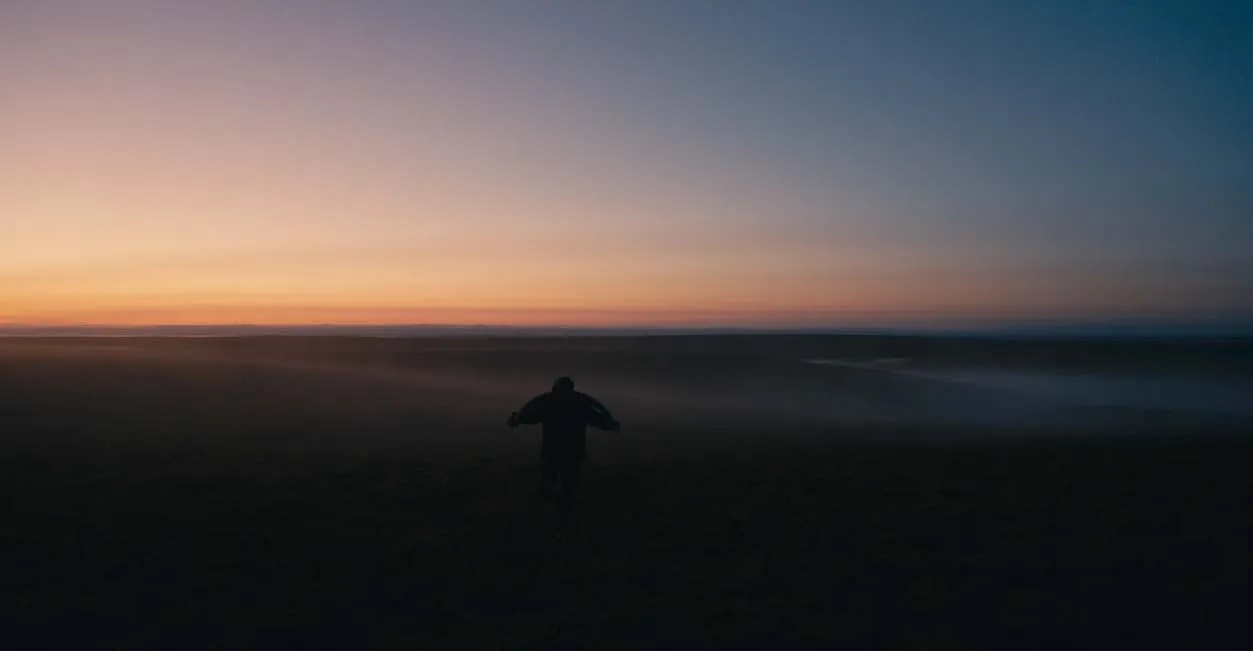 A figure moves through the tundra at twilight.